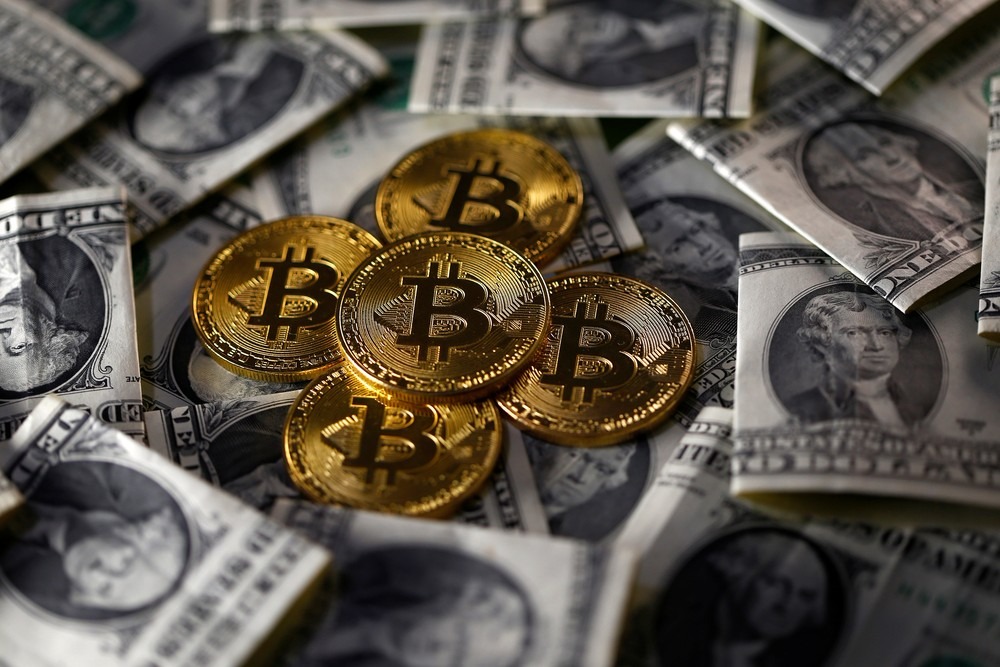 Moeda ilustrativa de bitcoin, em meio a notas de dólar. (Foto: Dado Ruvic/Reuters)