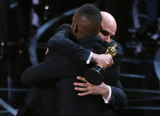 Empresa responsável por envelopes do Oscar pede desculpas por confusão Barry Jenkins, diretor de 'Moonlight', abraça o produtor Jordan Horowitz, de 'La la land', após lerem o nome errado do melhor filme no Oscar (Foto: Lucy Nicholson/Reuters)
