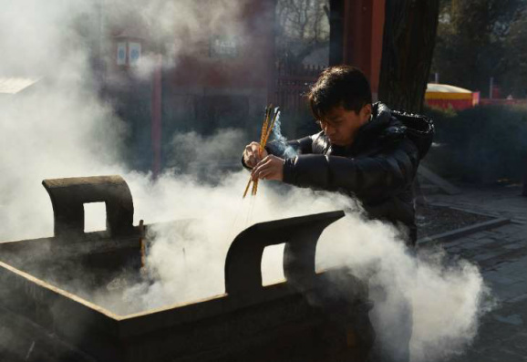 © Fornecido por AFP Chinês queima incenso nas comemorações do Ano Novo Lunar, durante o qual aconteceu o episódio com o bebê que reviveu