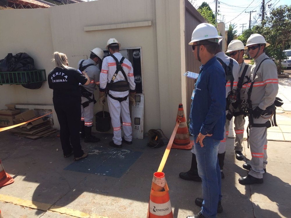 Funcionários da concessionária de energia e peritos da Polícia Civil avaliam relógio (Foto: Graziela Rezende)