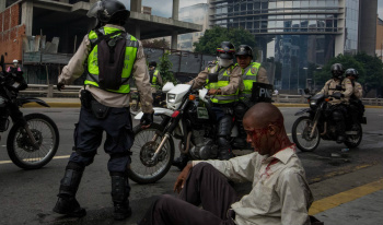 Homem ferido junto a policiais da Guarda Nacional Bolivariana. M. G. (EFE)