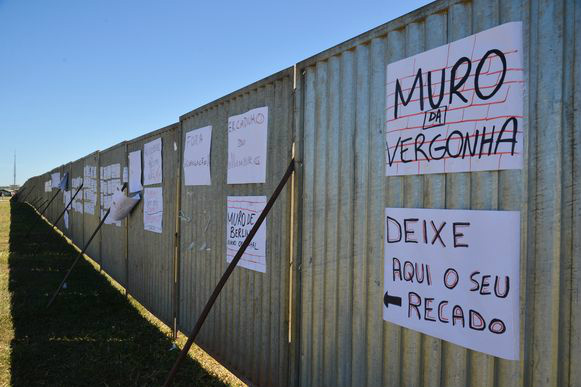 Estrutura com tapumes de aço no meio do gramado da Esplanada, erguido para que manifestantes favoráveis e contrários ao pedido de impeachment possam acompanhar a votação, recebe cartazes (Foto: André Cruz/Agência Brasil)
