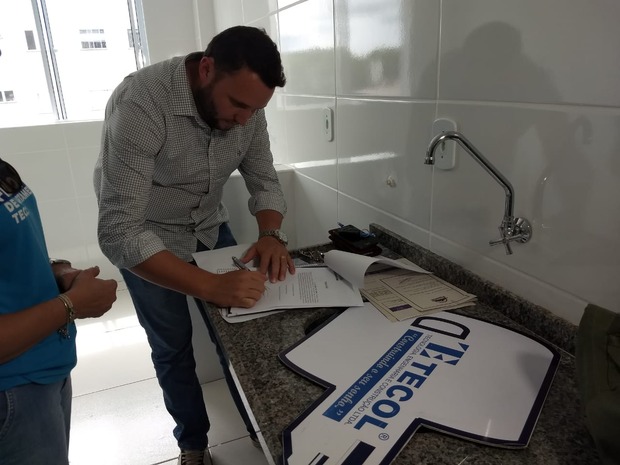 Leandro assinando o contrato na casa nova (Lucas Arruda)