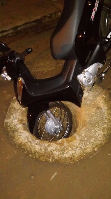 Moto fica presa ao cair em bueiro sem tampa no meio da rua Foto: Ligado na Redação/Dourados News