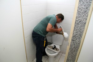 Servidor revisando a parte hidráulica para liberar banheiro interditado. (Foto: Marlon Ganassin/PMCG)