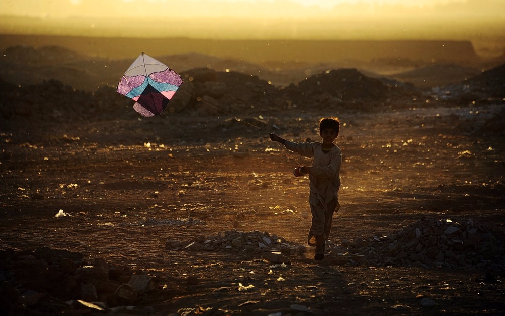 Criança brinca com uma pipa nos arredores de Herat, no Afeganistão (Foto: Aref Karimi / AFP Photo)