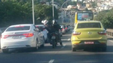 Os homens se aproximam do carro branco e o carona bate no vidro Foto: Ubiratan Gomes Costa / Foto do leitor
