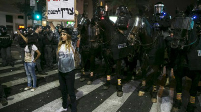 Manifestante segura cartaz em frente à linha de policiais montados em cavalos Foto: BAZ RATNER/REUTERS
