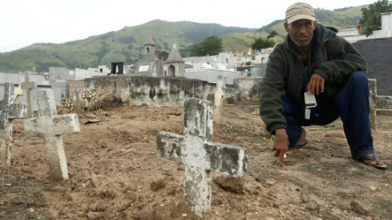 Israel Leite da Silva, de 48 anos, posa diante da cova onde estaria enterrado: 