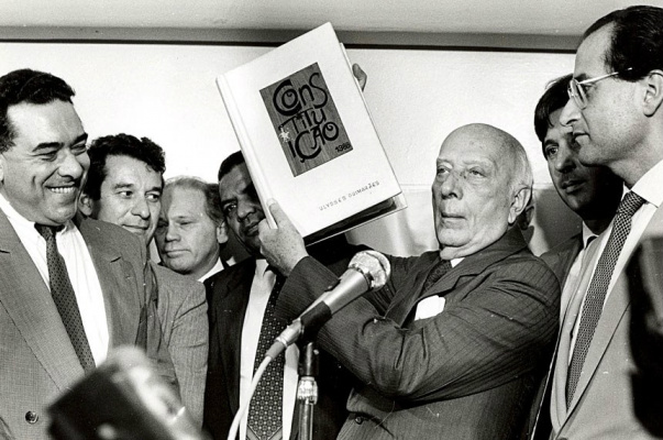 Senadores comemoram 28 anos da Constituição cidadã Cercado de parlamentares, o deputado Ulysses Guimarães (1916-1992) ergue a Constituição de 1988. Agência Senado