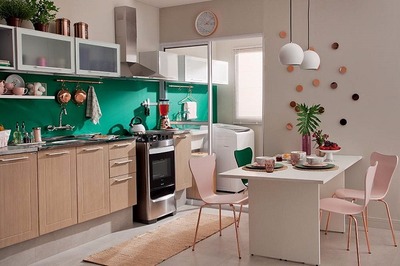 Na lavanderia, a faixa verde, os armários aéreos idênticos aos da cozinha e a decoração com elementos em cobre reforçam a integração entre os cômodos - Crédito: Divulgação
