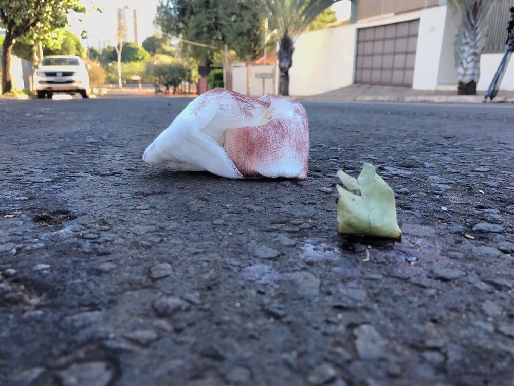 Jovem é baleada por ladrões em carro com desconhecidos na Capital No asfalto, sangue e material de socorro à jovem baleada (Foto: Osni Miranda)