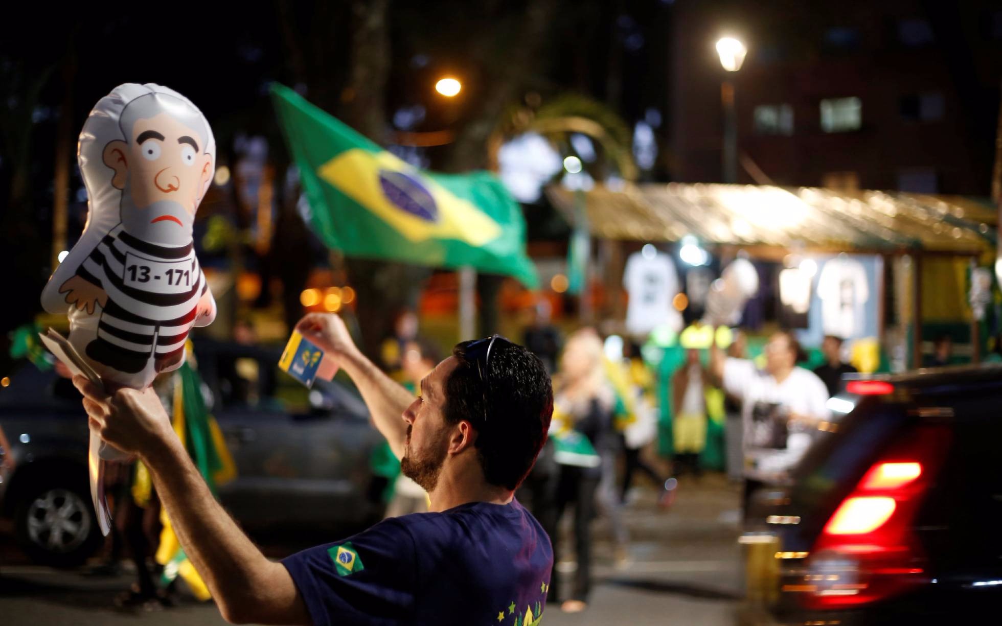 Um homem sustenta o 'Pixuleco', o balão do ex-presidente Lula vestido como um réu em uma manifestação em Curitiba. REUTERS