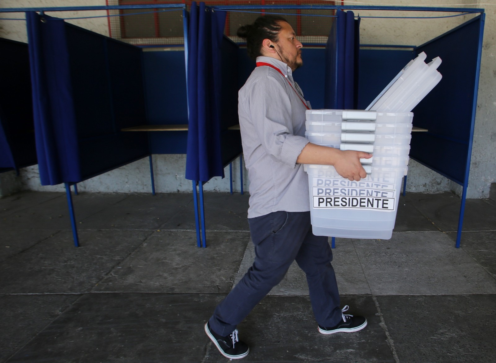 Funcionário eleitoral carrega urnas em preparação para o segundo turno presidencial em um estádio de Santiago, no Chile (Foto: Claudio Reyes/ AFP)