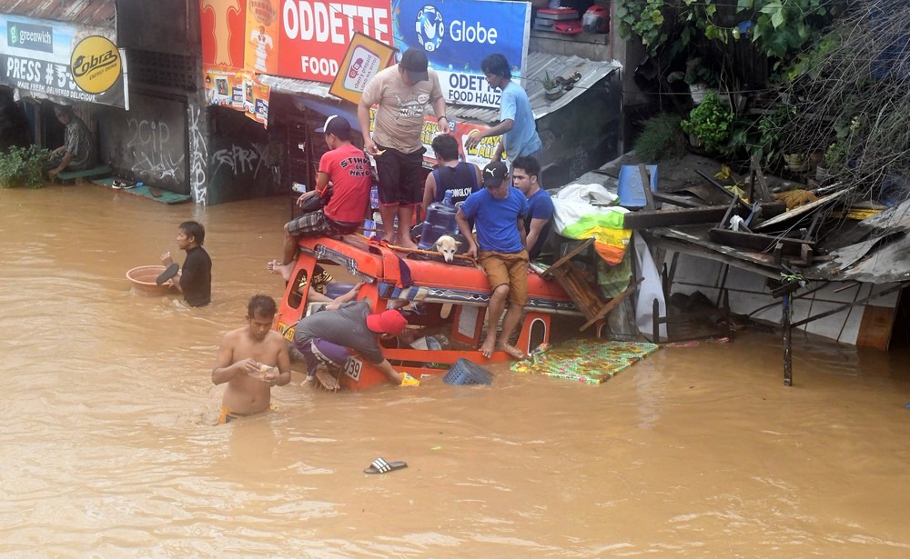 Moradores no topo de um veículo parcialmente submerso em uma estrada inundada na cidade de Cagayan de Oro, nas Filipinas (Foto: REUTERS / Froilan Gallardo)