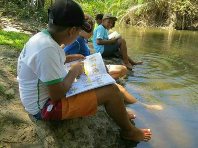 Estudantes têm aula na beira de lago devido ao calor
